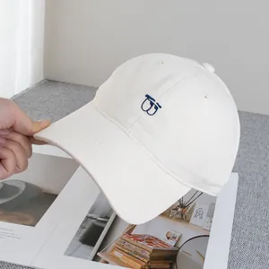 Dettaglio del cappellino in cotone crema con ricamo blu e cuciture sulla visiera