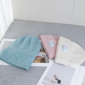 Detailed knit texture of wool beanies in light blue, pink and beige with brand label
