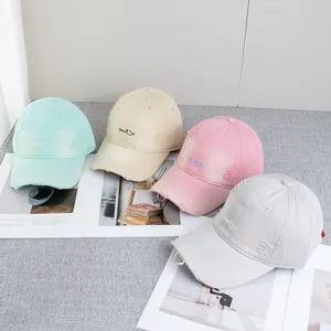 Detail of distressed baseball caps with Smile embroidery in pastel macaron colors
