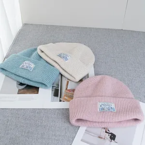 Detailed close-up of ribbed wool blend knit beanies in blue, beige, and pink colors