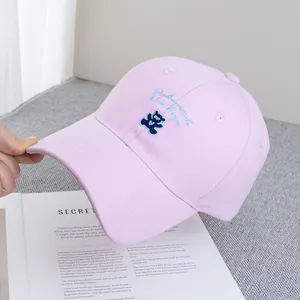 Detailed embroidery of a blue bear on a light pink cotton twill baseball cap fabric