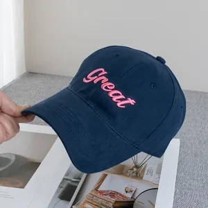Detail of pink embroidered Great letters on a navy blue canvas baseball cap fabric