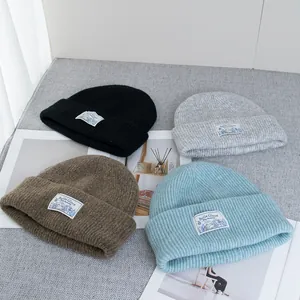 Flat lay of wool knit beanies in blue, grey, and black with woven mountain labels