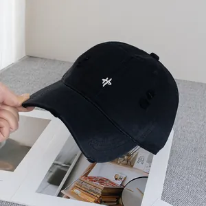 Close-up of a distressed black baseball cap with white embroidery and frayed details