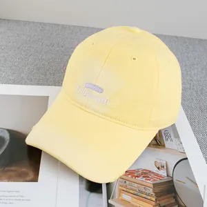 Detailed close-up of vintage yellow baseball cap with purple and white embroidery