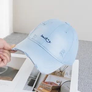 Detail of distressed light blue baseball cap with smile embroidery and ripped texture