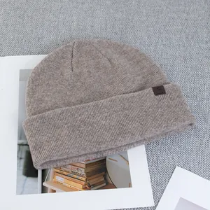 Detail of wool knit beanie with premium brown leather logo patch on textured fabric