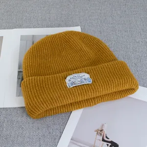 Close-up of ginger ribbed wool beanie with a mountain graphic brand label on the fold