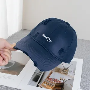 Detailed view of navy blue distressed baseball cap with white Smile embroidery