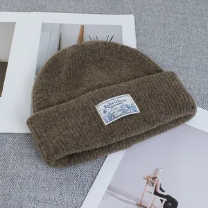 Detail of wool blend beanie texture with embroidered mountain brand label on a magazine