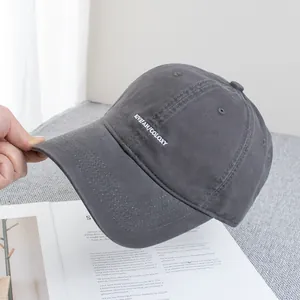 Detailed embroidery on dark gray canvas baseball cap resting on a magazine