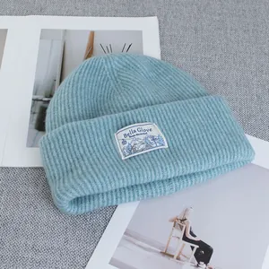 Close-up of the light blue ribbed knit texture and white fabric label on the wool beanie