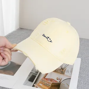 Macro view of distressed yellow baseball cap with blue Smile embroidery details