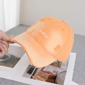 Detail of embroidered Smile text on distressed orange vintage style baseball cap
