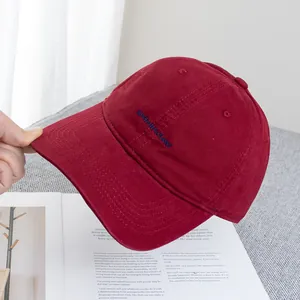 Close-up of deep red canvas baseball cap with blue letter embroidery and neat stitching