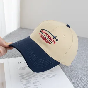 Dettaglio del ricamo rosso sul cappellino da baseball in cotone beige e blu