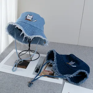 Detail view of denim bucket hat with raw edges and cute cat embroidery patches