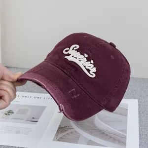 Détail d'une casquette de baseball vintage bordeaux avec broderie et bord usé