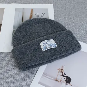 Detailed close-up of wool knit beanie texture with an elegant winter landscape woven label