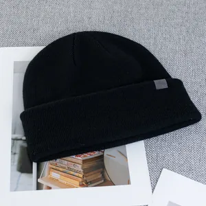 Detailed view of black wool knit beanie featuring a grey woven mountain logo tag