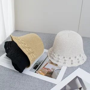 Trois bobs en tricot à bords ondulés noir, kaki et beige sur tissu gris élégant