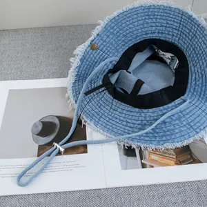Light blue denim bucket hat with frayed edges and adjustable windproof chin strap