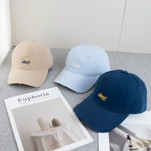 Three vintage baseball caps with letter embroidery in khaki, light blue, and navy blue