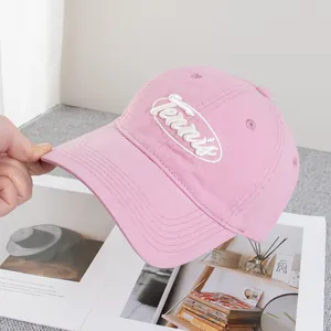 Gros plan sur la broderie Tennis blanche sur une casquette de baseball rose pâle