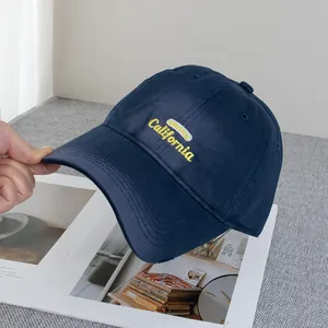 Detail of embroidered yellow California text on a navy blue vintage cotton baseball cap