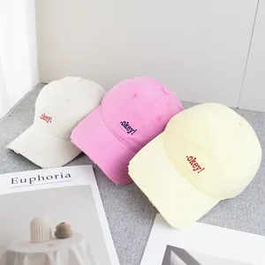 Three distressed cotton baseball caps in beige, pink and yellow with .okey! embroidery