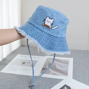 Close-up of cat embroidery and frayed edge detail on light blue denim sun hat