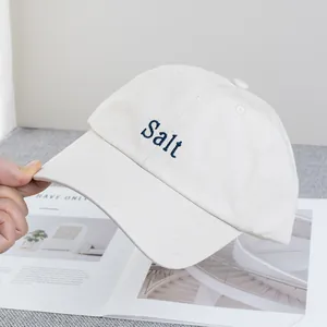 Détail de la broderie Salt sur une casquette en coton crème avec coutures premium