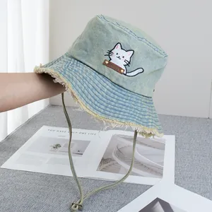 Detail view of washed denim bucket hat with cat embroidery and frayed edges