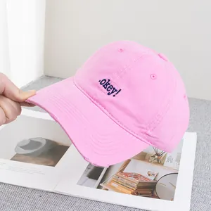 Detail of pink baseball cap featuring blue okey embroidery and distressed brim edge