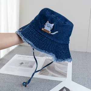 Detail view of denim bucket hat with gray cat embroidery and rustic frayed edges