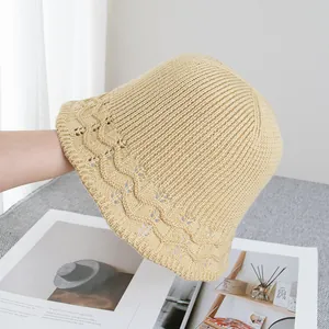 Détail du chapeau en tricot beige montrant le bord ondulé et la texture ajourée