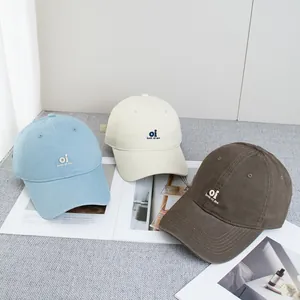 Three embroidered cotton baseball caps in light blue, beige, and brown with curved brims