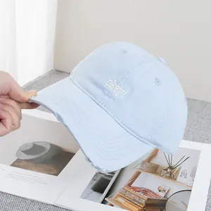Detailed close-up of light blue cotton baseball cap with okey embroidery and distressed edges