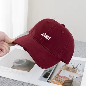 Detailed macro view of embroidered text and distressed brim on maroon baseball cap
