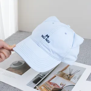 Close-up of cat ear baseball cap with NIU NIU embroidery and blue canvas texture