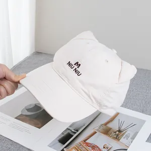 Detailed close-up of cat ear design and letter embroidery on beige cotton baseball cap