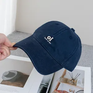 Close-up of navy blue cotton baseball cap with white 'oi' embroidery on magazine background