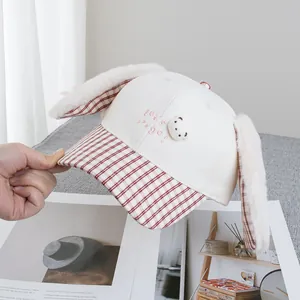 Detail of plush bunny ears and cute 3D bear patch on a white cartoon baseball cap