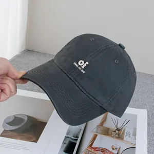 Detail of embroidered 'oi look at me' text on dark grey cotton twill baseball cap