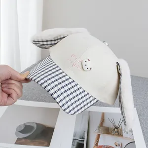 Detail of plush bunny ears and let's go embroidery on a cream cartoon baseball cap