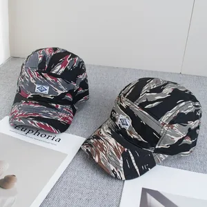 Détail de deux casquettes camouflage avec étiquette OSCAPS sur une surface texturée