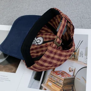 Détail d'une casquette vintage à carreaux avec boucle en bronze réglable et gravure artisanale