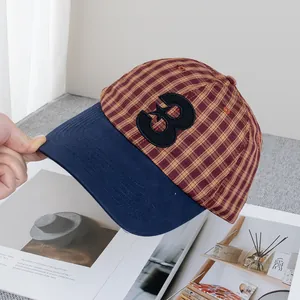 Détail de la casquette à carreaux avec broderie numéro 3 et visière bleu marine