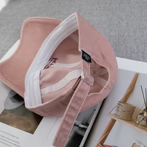 Detail of pink cotton baseball cap showing internal branding and adjustable metal strap