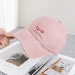 Close-up of pink cotton baseball cap with red embroidered Backing text and stitching